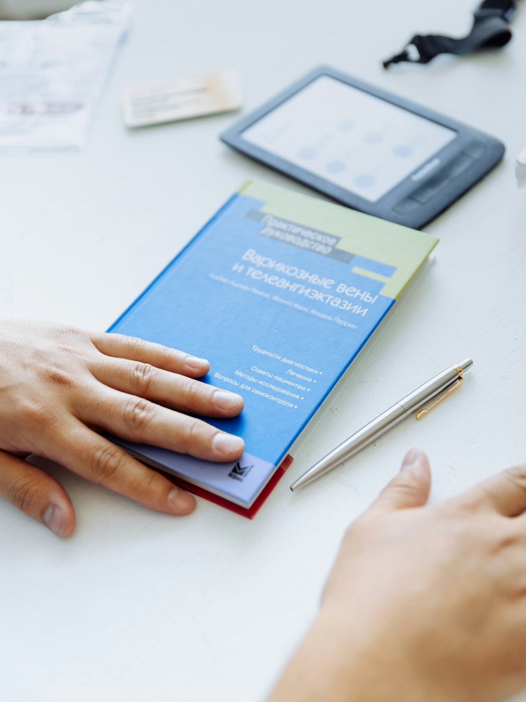 service-06 a-persons-hand-on-a-blue-folder-next-to-a-tablet-innu-y-voc